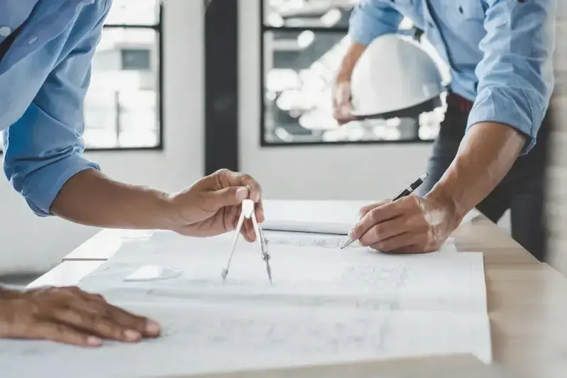 Un grupo de arquitectos discutiendo planos de construcción en una reunión.